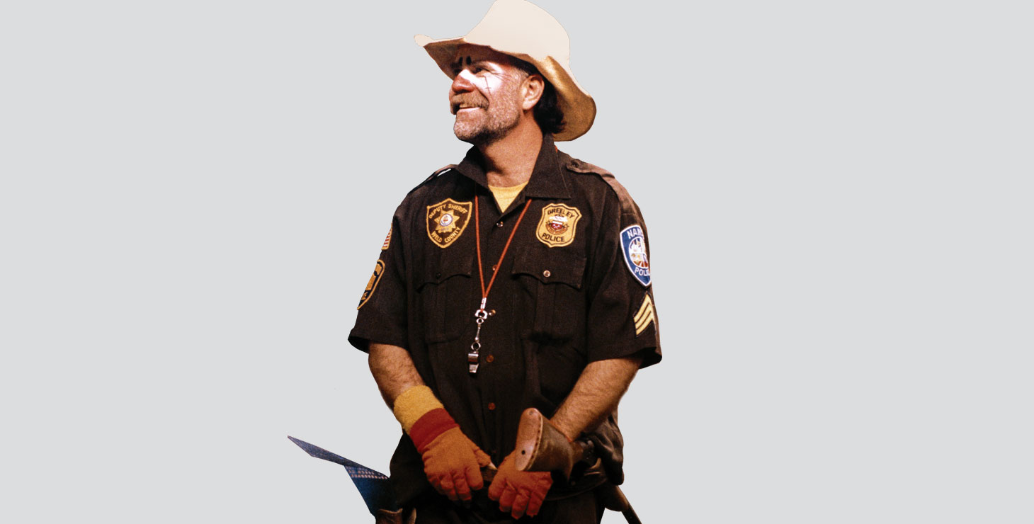 Tom Feller dressed as a rodeo clown, smiling and looking away.